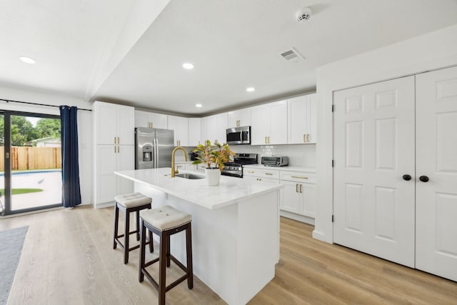 1833 Chamberlain Dr, Carrollton, TX 75007 - kitchen with appliances with stainless steel finishes, a sink, a breakfast bar area, light wood-style flooring, and white cabinetry