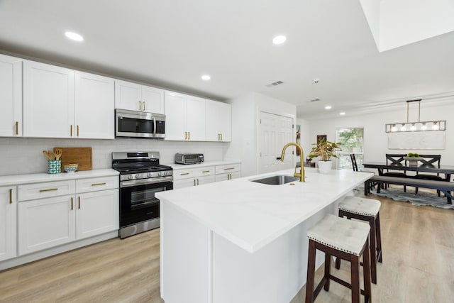1833 Chamberlain Dr, Carrollton, TX 75007 - kitchen with appliances with stainless steel finishes, a sink, light wood-style flooring, a kitchen breakfast bar, and recessed lighting