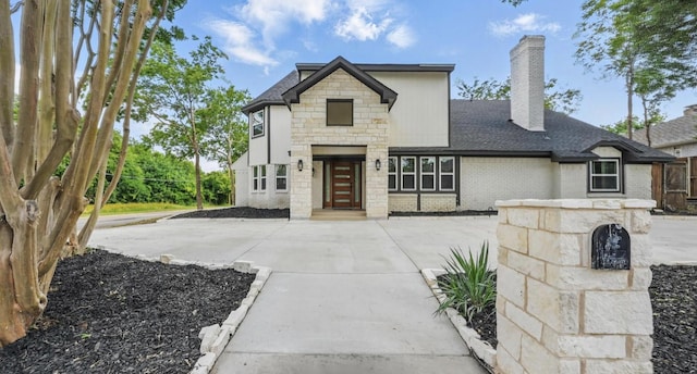 9690 Fallbrook Dr, Dallas, TX 75243 - view of front facade with a chimney, brick siding, a shingled roof, and stone siding