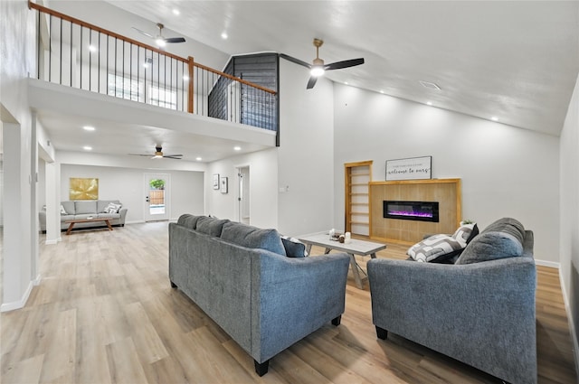 9690 Fallbrook Dr, Dallas, TX 75243 - living room featuring a ceiling fan, a glass covered fireplace, wood finished floors, a towering ceiling, and recessed lighting