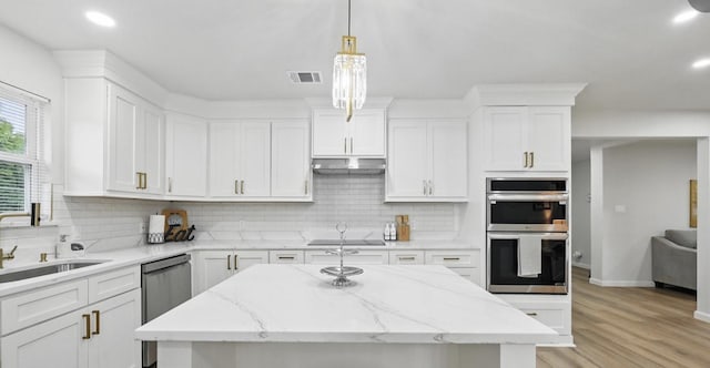 9690 Fallbrook Dr, Dallas, TX 75243 - kitchen featuring appliances with stainless steel finishes, tasteful backsplash, white cabinetry, light wood-style flooring, and a kitchen island