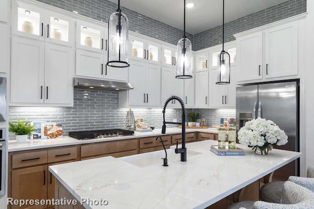 11749 Edgewood Dr, Justin, TX 76247 - kitchen with under cabinet range hood, decorative light fixtures, stainless steel appliances, white cabinets, and a breakfast bar area
