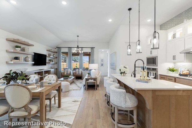 11749 Edgewood Dr, Justin, TX 76247 - kitchen with appliances with stainless steel finishes, glass insert cabinets, light countertops, light wood-type flooring, and pendant lighting