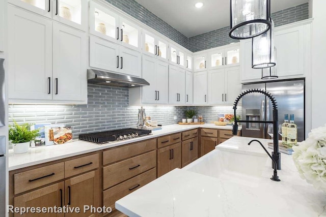 11749 Edgewood Dr, Justin, TX 76247 - kitchen with stainless steel appliances, under cabinet range hood, white cabinets, and hanging light fixtures