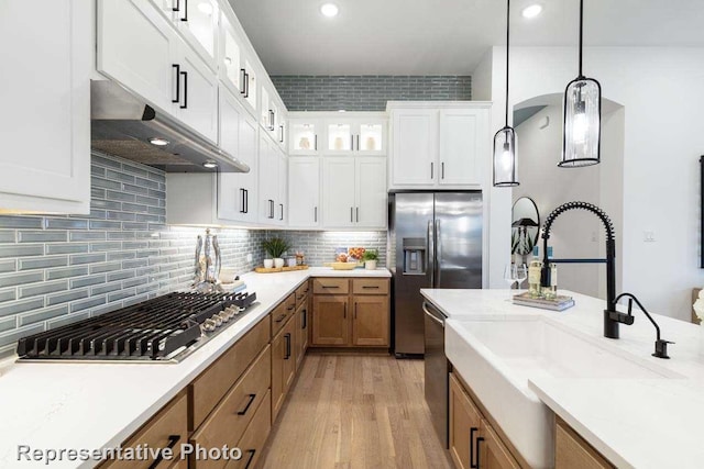 11749 Edgewood Dr, Justin, TX 76247 - kitchen featuring under cabinet range hood, appliances with stainless steel finishes, a sink, hanging light fixtures, and brown cabinets