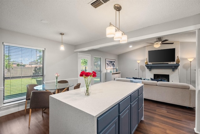 2937 Lake Park Dr, Grand Prairie, TX 75052 - kitchen featuring blue cabinetry, dark wood-style flooring, a large fireplace, a textured ceiling, and healthy amount of natural light