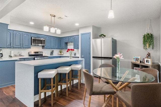 2937 Lake Park Dr, Grand Prairie, TX 75052 - kitchen with blue cabinets, stainless steel appliances, light countertops, decorative backsplash, and dark wood-type flooring