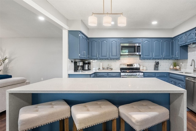 2937 Lake Park Dr, Grand Prairie, TX 75052 - kitchen with appliances with stainless steel finishes, blue cabinetry, a kitchen bar, and recessed lighting