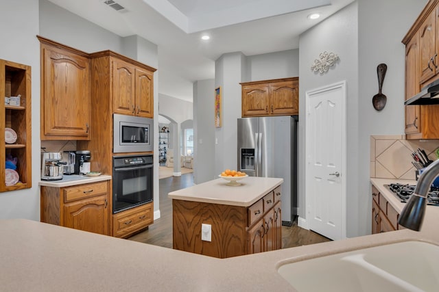 6504 Bluebird Dr, Arlington, TX 76001 - kitchen with appliances with stainless steel finishes, arched walkways, dark wood finished floors, recessed lighting, and brown cabinetry
