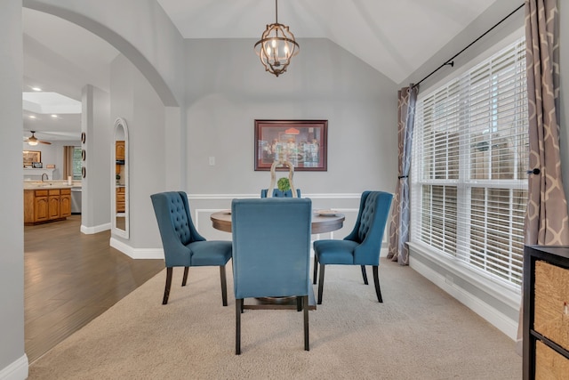 6504 Bluebird Dr, Arlington, TX 76001 - dining space featuring arched walkways, a chandelier, vaulted ceiling, wood finished floors, and baseboards