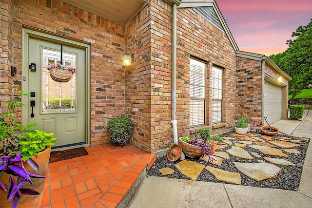 616 Crowley Rd, Arlington, TX 76012 - exterior entry at dusk featuring brick siding, a garage, and concrete driveway