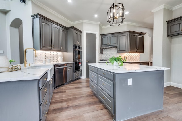 2007 Hill Country Ct, Arlington, TX 76012 - kitchen featuring appliances with stainless steel finishes, arched walkways, light stone counters, a kitchen island, and a chandelier