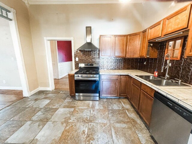 211 W Saunders St, Trenton, TX 75490 - kitchen with appliances with stainless steel finishes, wall chimney range hood, tile counters, crown molding, and a sink