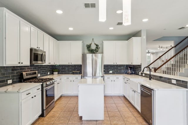 5708 Pebble Ridge Dr, Mckinney, TX 75070 - kitchen with appliances with stainless steel finishes, a sink, tasteful backsplash, a peninsula, and white cabinetry