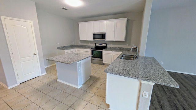 4110 Sandalwood Ct, Forney, TX 75126 - kitchen with appliances with stainless steel finishes, a sink, a peninsula, a center island, and white cabinetry