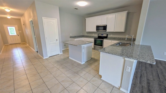 4110 Sandalwood Ct, Forney, TX 75126 - kitchen featuring stainless steel appliances, a sink, a center island, light stone counters, and light tile patterned floors