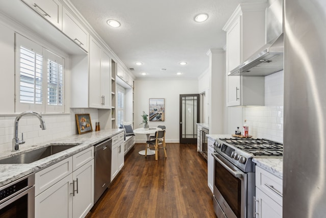 5510 Monticello Ave, Dallas, TX 75206 - kitchen with appliances with stainless steel finishes, a sink, wall chimney exhaust hood, white cabinets, and recessed lighting