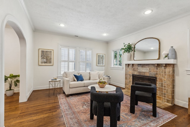5510 Monticello Ave, Dallas, TX 75206 - living area with a tile fireplace, arched walkways, dark wood-type flooring, ornamental molding, and baseboards
