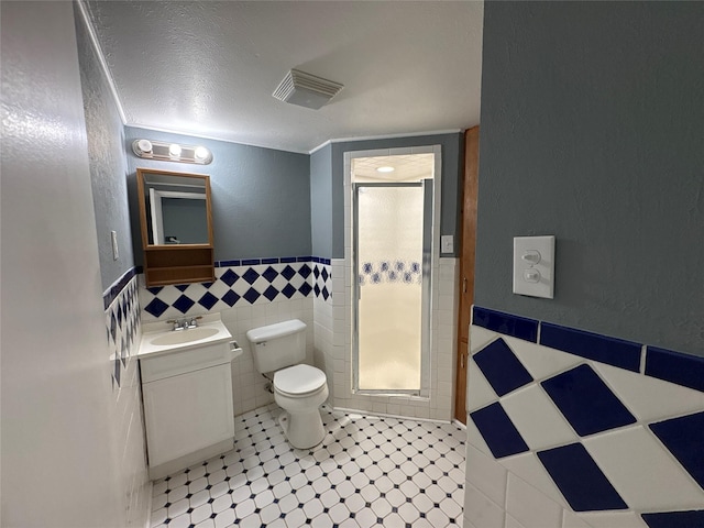 2401 N Alexander St, Sherman, TX 75092 - bathroom with tile walls, a shower with shower door, vanity, toilet, and wainscoting