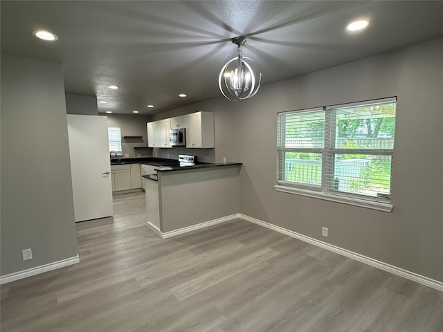 2401 N Alexander St, Sherman, TX 75092 - kitchen with stainless steel appliances, a peninsula, light wood finished floors, dark countertops, and white cabinets
