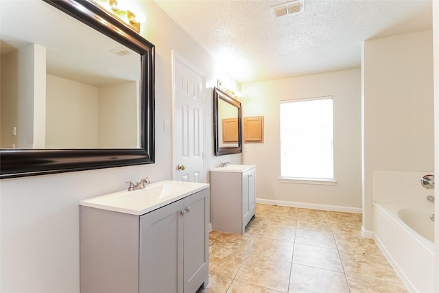 226 Miramar Dr, Arlington, TX 76002 - full bath featuring two vanities, a bath, a textured ceiling, tile patterned floors, and baseboards