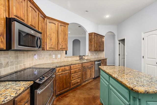 106 Versailles Ln, Aledo, TX 76008 - kitchen featuring appliances with stainless steel finishes, tasteful backsplash, arched walkways, a center island, and light stone counters