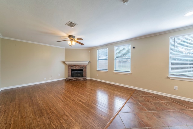12916 Gillon Dr, Frisco, TX 75035 - unfurnished living room featuring a ceiling fan, baseboards, a brick fireplace, crown molding, and wood finished floors