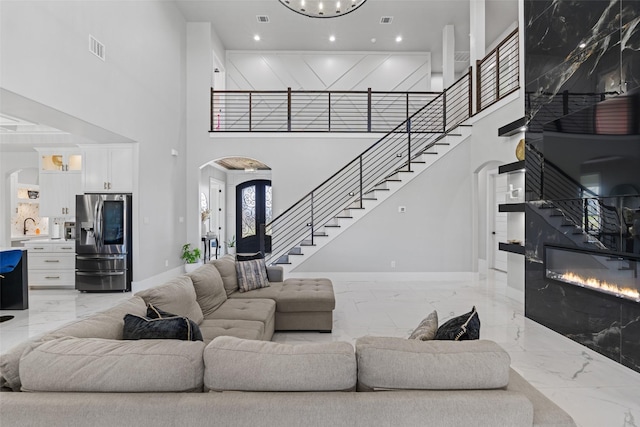 10901 Chriswood Dr, Crowley, TX 76036 - living room featuring light marble finish flooring, stairs, a towering ceiling, baseboards, and arched walkways