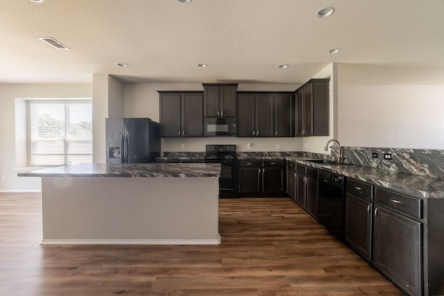 9233 Benevolent Ct, Providence Village, TX 76227 - kitchen featuring black appliances, a sink, a center island, dark wood-type flooring, and recessed lighting