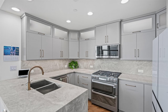 500 Throckmorton St Unit 2707, Fort Worth, TX 76102 - kitchen with stainless steel appliances, a sink, a peninsula, wood finished floors, and glass insert cabinets