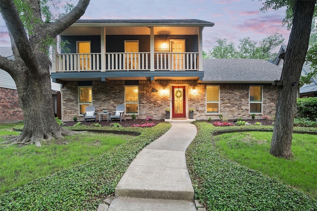 9030 Summer Glen Ln, Dallas, TX 75243 - front facade featuring a balcony, a front yard, a shingled roof, covered porch, and brick siding