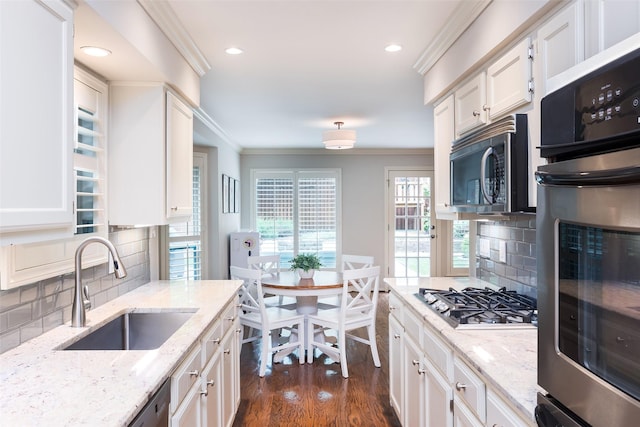 9030 Summer Glen Ln, Dallas, TX 75243 - kitchen featuring stainless steel appliances, a sink, white cabinetry, ornamental molding, and dark wood-style flooring