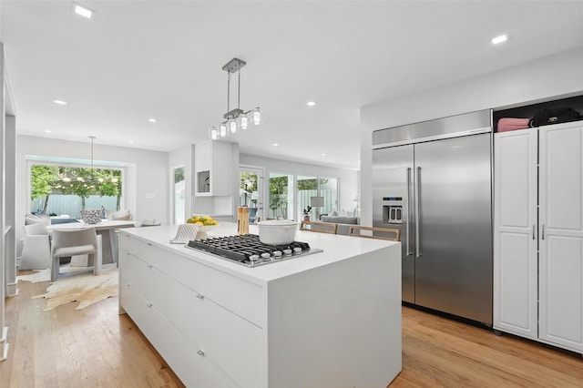 4356 San Carlos St, University Park, TX 75205 - kitchen featuring stainless steel appliances, white cabinetry, a kitchen island, light wood finished floors, and decorative light fixtures