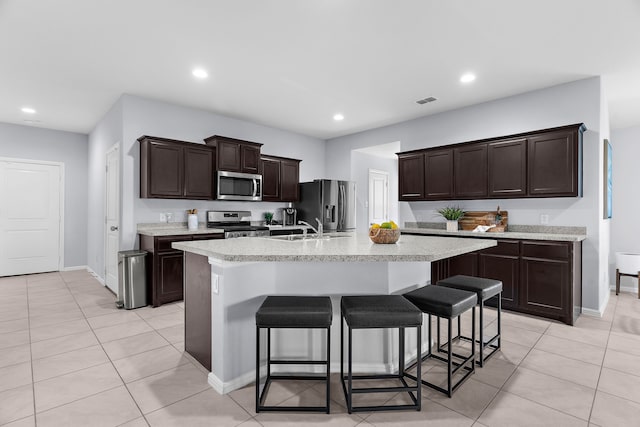 16316 Caledonia Ct, Justin, TX 76247 - kitchen featuring stainless steel appliances, a kitchen bar, light countertops, a center island with sink, and light tile patterned floors