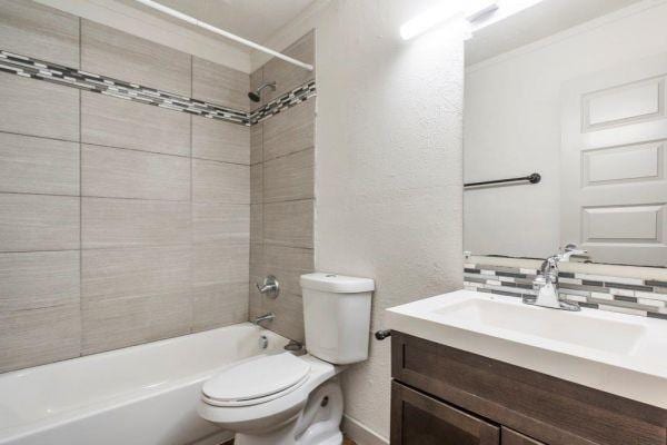 2320 W Prairie St, Denton, TX 76201 - bathroom with ornamental molding, toilet, a textured wall, vanity, and shower / tub combination
