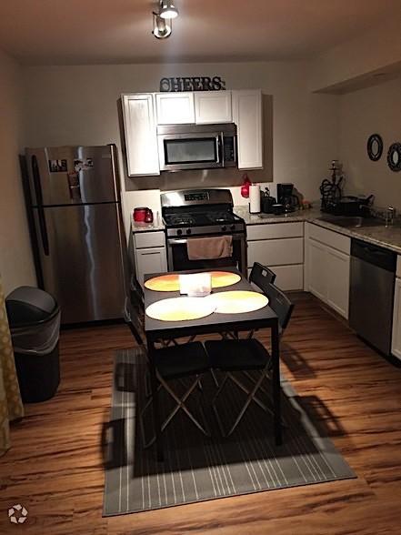 2320 W Prairie St, Denton, TX 76201 - kitchen with stainless steel appliances, dark wood finished floors, white cabinets, a sink, and light countertops