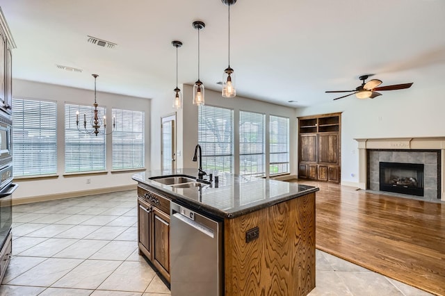 7341 Chadwick Dr, Mckinney, TX 75072 - kitchen with stainless steel dishwasher, a sink, light tile patterned flooring, a ceiling fan, and a fireplace