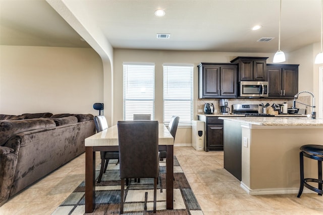 5212 Sugarcane Ln, Fort Worth, TX 76179 - kitchen with appliances with stainless steel finishes, dark brown cabinets, open floor plan, a sink, and backsplash
