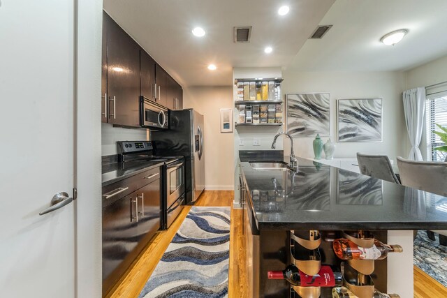 5806 Birchbrook Dr Unit 203, Dallas, TX 75206 - kitchen featuring open shelves, stainless steel appliances, a sink, dark countertops, and light wood-style flooring