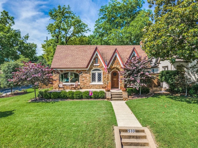 533 Newell Ave, Dallas, TX 75223 - tudor house with stone siding, a front yard, and a chimney