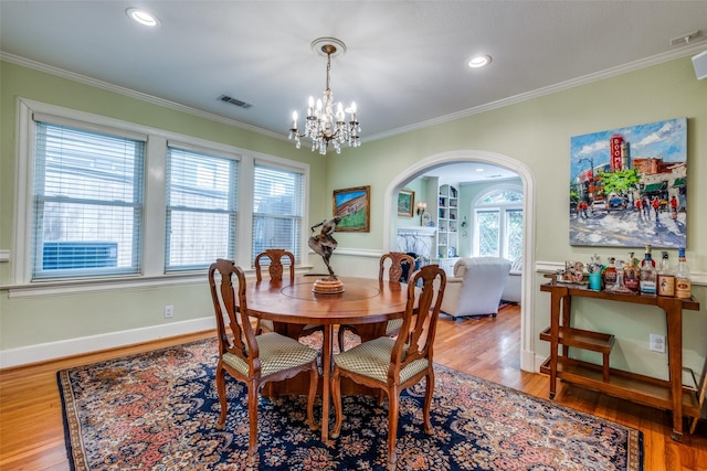 533 Newell Ave, Dallas, TX 75223 - dining room featuring arched walkways, a chandelier, wood finished floors, crown molding, and baseboards