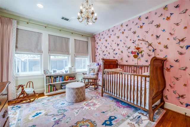 533 Newell Ave, Dallas, TX 75223 - bedroom featuring ornamental molding, baseboards, wood finished floors, a nursery area, and a chandelier