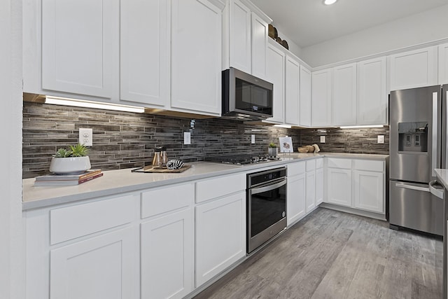 9305 Derry Ln, Aubrey, TX 76227 - kitchen with stainless steel appliances, white cabinetry, light wood finished floors, light countertops, and backsplash