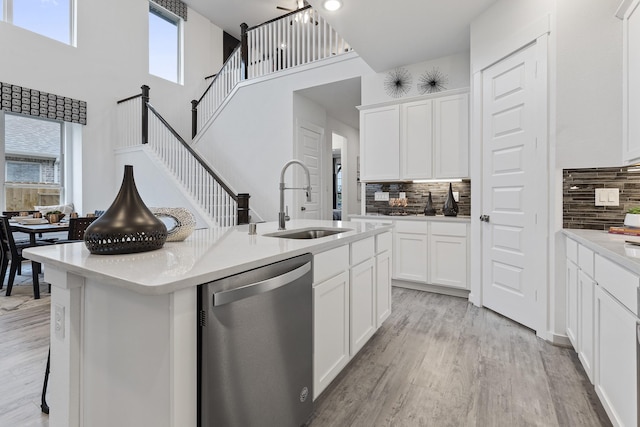 9305 Derry Ln, Aubrey, TX 76227 - kitchen featuring stainless steel dishwasher, a sink, decorative backsplash, light wood-style floors, and a high ceiling