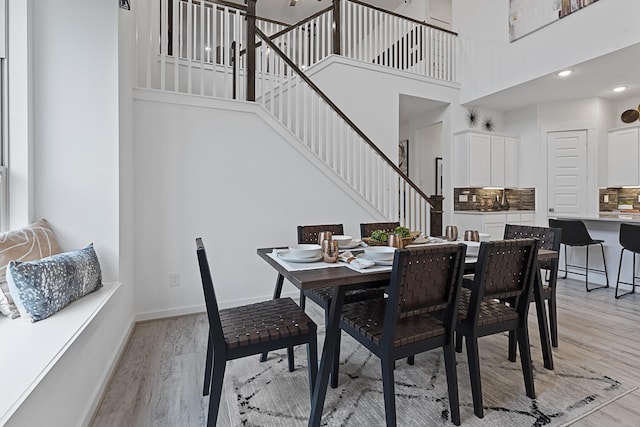 9305 Derry Ln, Aubrey, TX 76227 - dining space with stairs, light wood-style floors, a high ceiling, and baseboards