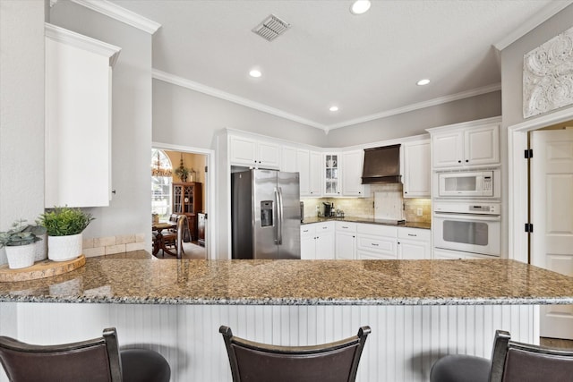 1300 Darbyton Dr, Hewitt, TX 76643 - kitchen with white appliances, custom range hood, stone countertops, a peninsula, and recessed lighting
