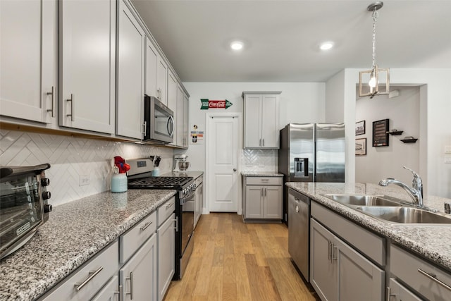 1224 Johnson Dr, Celina, TX 75009 - kitchen featuring appliances with stainless steel finishes, a sink, gray cabinets, light wood-type flooring, and recessed lighting