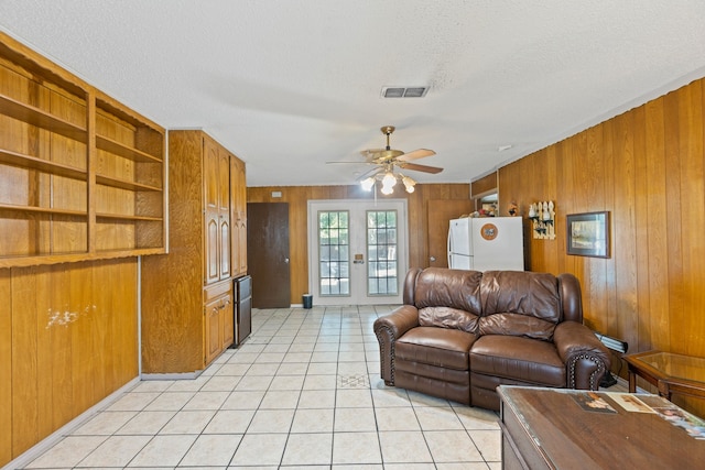 100 Yorkshire Dr, Princeton, TX 75407 - living area featuring french doors, wood walls, a ceiling fan, light tile patterned flooring, and a textured ceiling