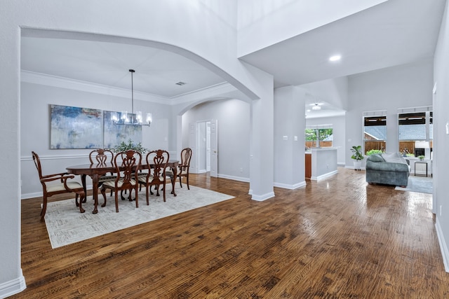 8905 Glen Garden Dr, Mckinney, TX 75072 - dining space with arched walkways, wood finished floors, a high ceiling, baseboards, and crown molding