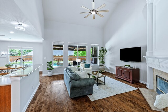 8905 Glen Garden Dr, Mckinney, TX 75072 - living area featuring high vaulted ceiling, ceiling fan, dark wood-type flooring, a tiled fireplace, and a chandelier
